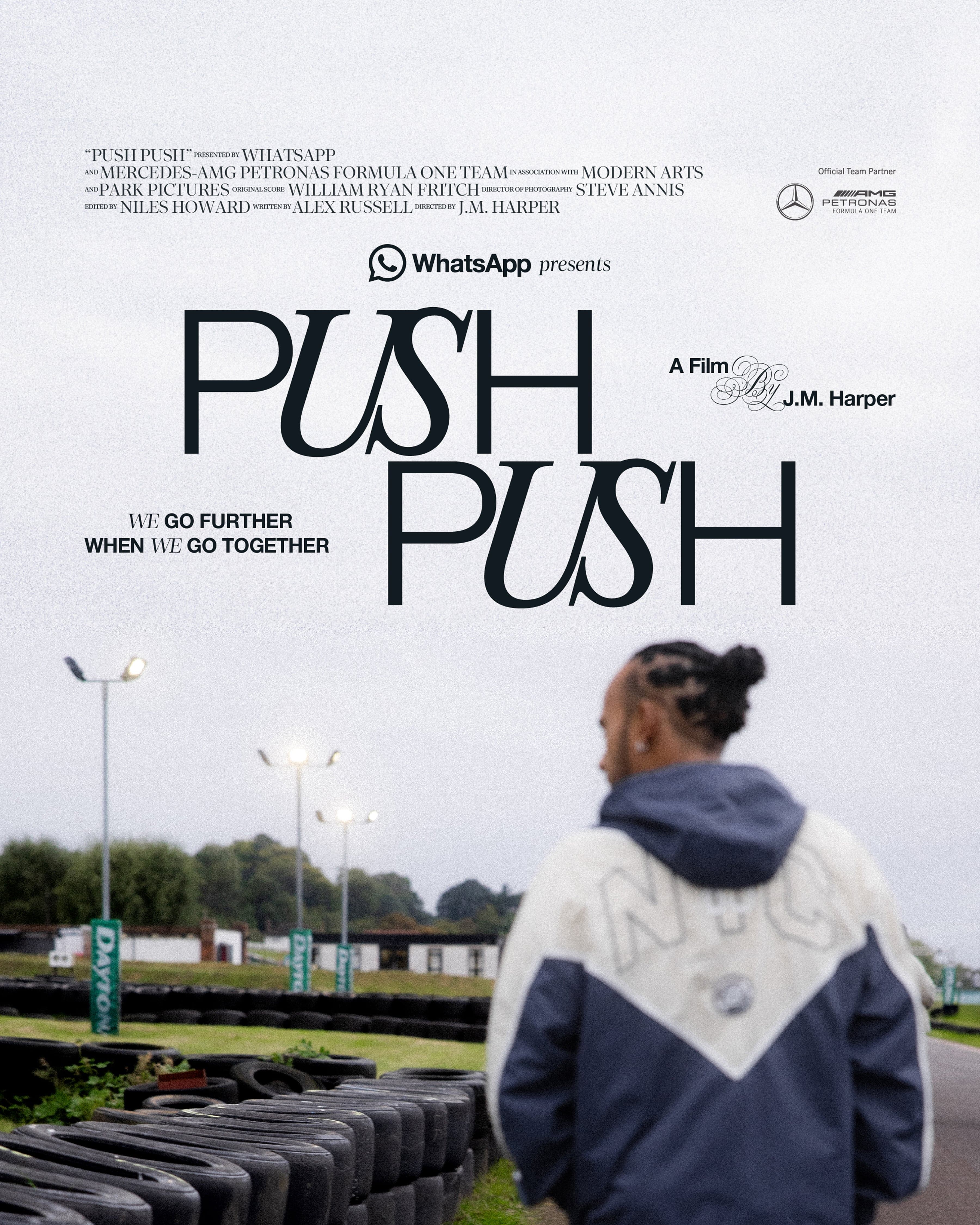 A person in a jacket stands near a racetrack with tire stacks. "Push Push" film poster text and logos are visible above.