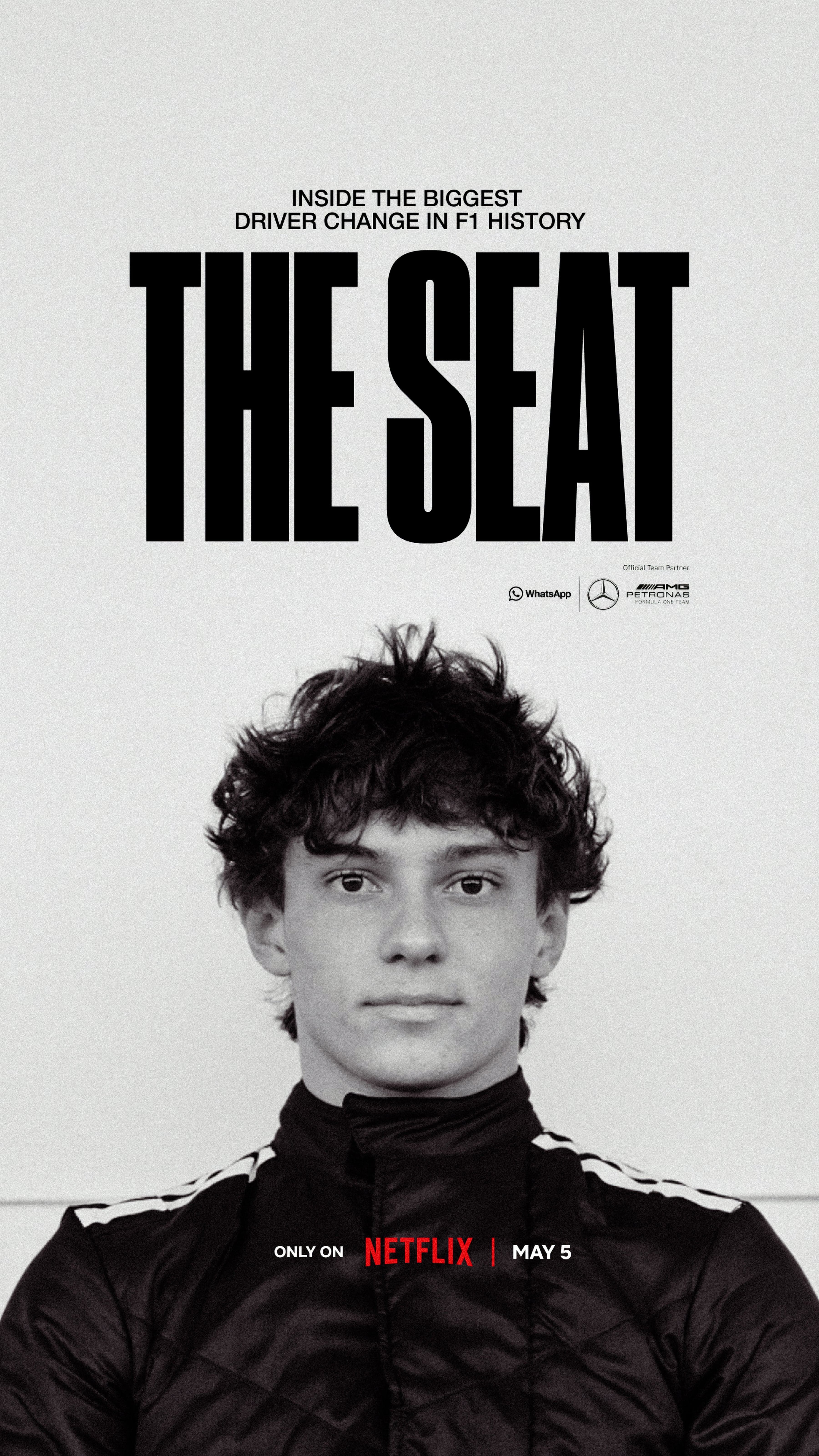 Young man with curly hair in a black jacket, centered against a white background. Text above reads "The Seat," promoting a Netflix release.