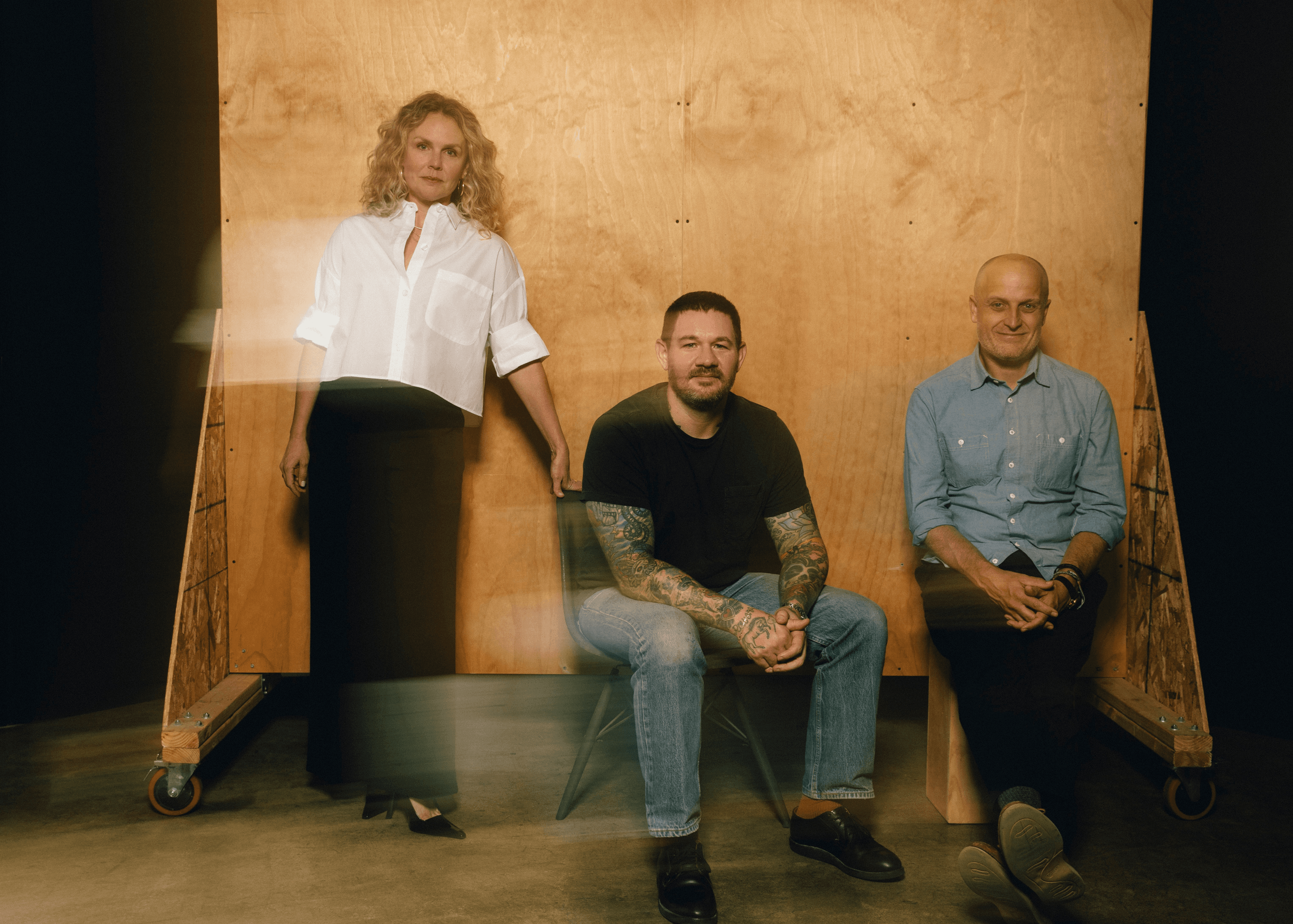 Three people posing in front of a wooden backdrop.