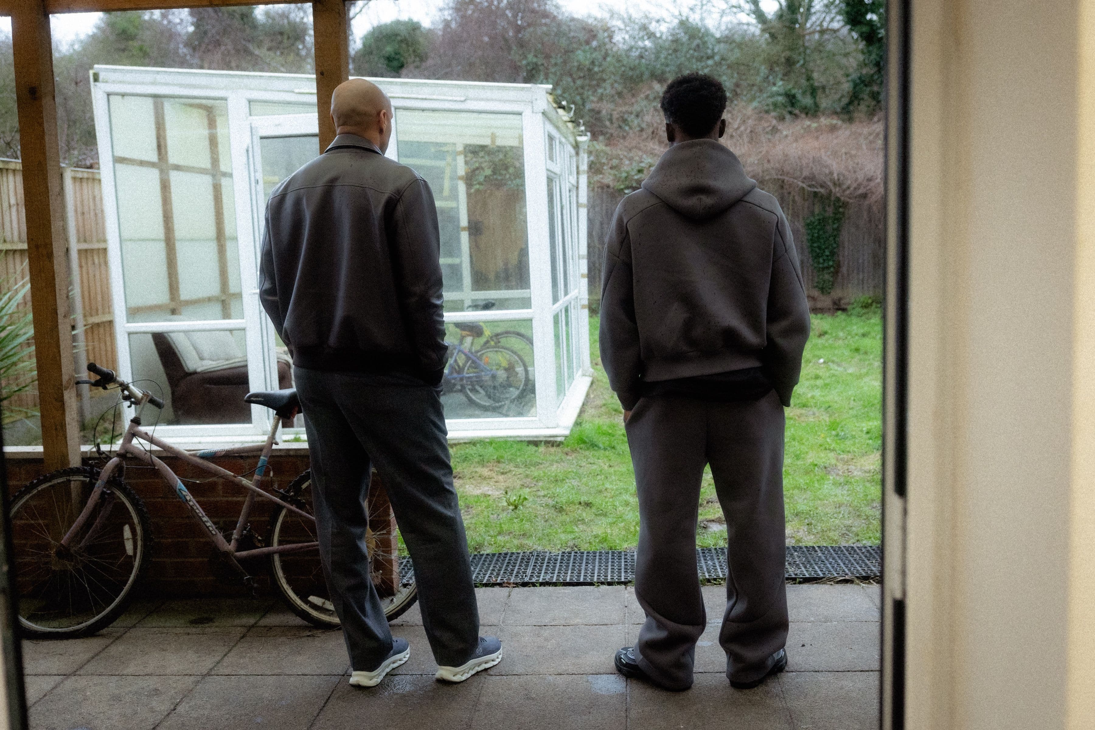 Two men standing an looking out at a backyard