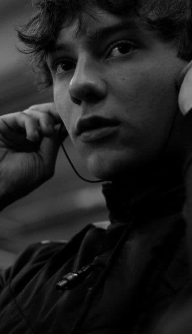 Person adjusting earphones, looking thoughtful, in black and white.