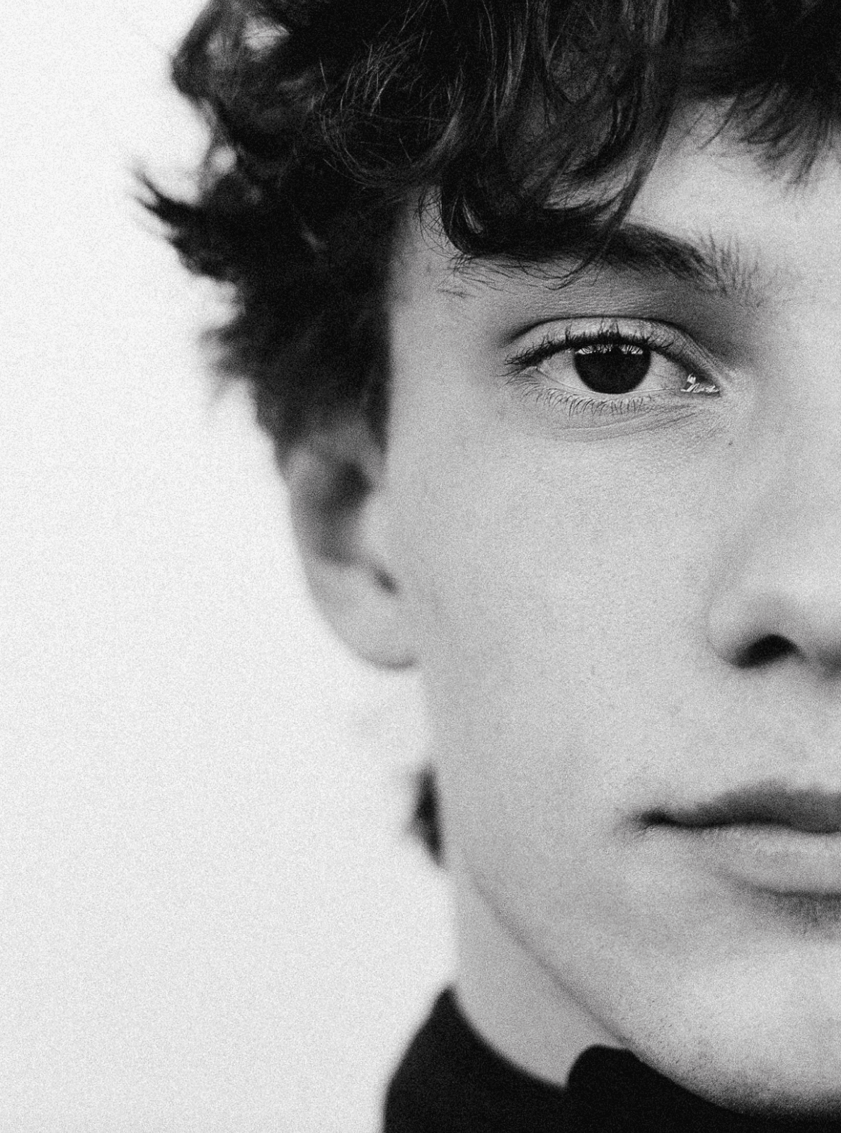 Close-up of a person's face, focusing on the eye and lips. Black and white.